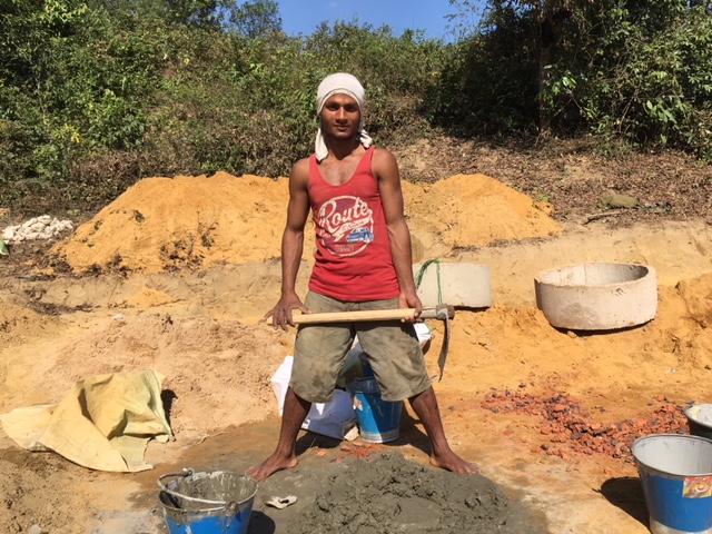 A Rohingyan man mixes cement for the construction of latrines for the new clinic.