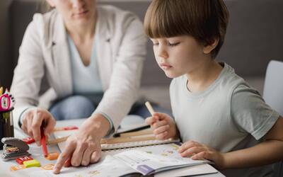 Immagine: vista-laterale-del-bambino-che-impara-dal-tutor-casa