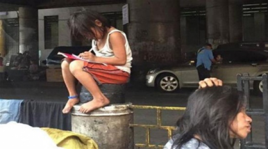 طفلة فقيرة تكتب وظيفتها في أحد الشوارع المكتظة