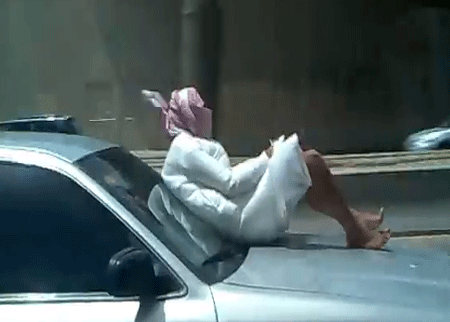 شاب يجلس فوق السيارة اثناء سيرها