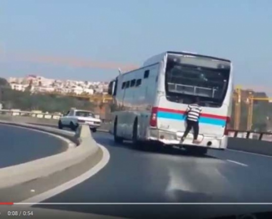 طفل يسافر متمسكاً بـ حافلة للركاب