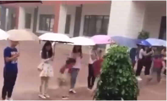 بالفيديو: مشهد مؤثر لمعلمين يقفون بمظلاتهم لينتقل الطلاب من مبنى لآخر بالفيديو: مشهد مؤثر لمعلمين يقفون بمظلاتهم لينتقل الطلاب من مبنى لآخر