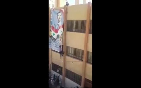 بالفيديو.. سقوط مؤيد للأسد تسلق سطح مدرسة ليرفع علم النظام