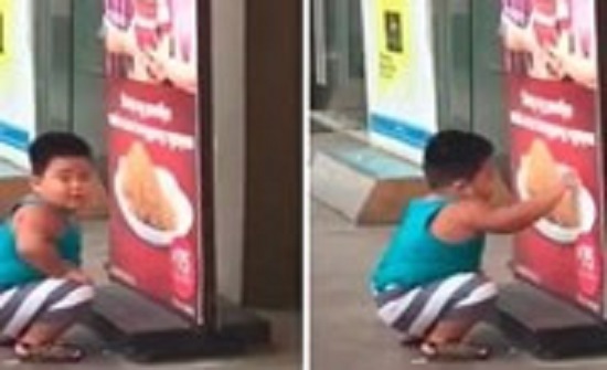 بالفيديو.. طفل جائع يحاول تناول الدجاج من ملصق إعلاني