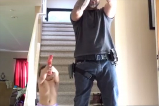 فيديو لشرطي يُعلِم إبنه الرضيع إستخدام السلاح .. والطفل ينفذ بدقه