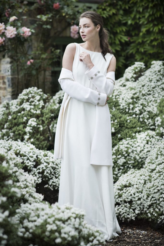 Cliff at Lyons shoot. Spring/summer 19 Bridal Inspiration. Bride amounst white flowers wearing a simple white dress and coat.