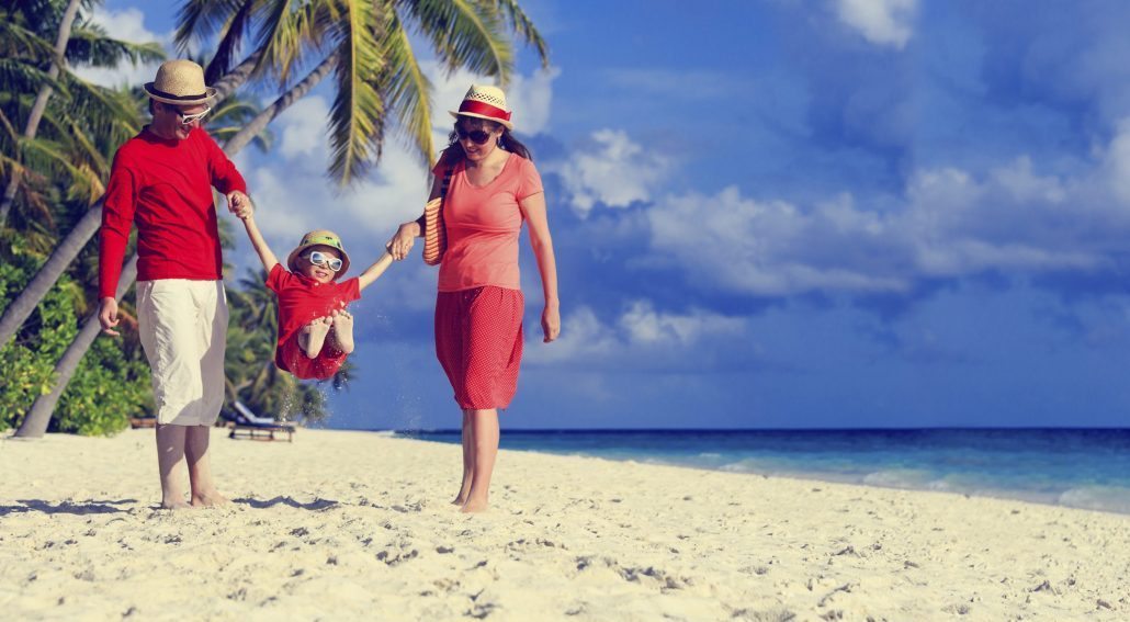 family with kid playing on sand beach