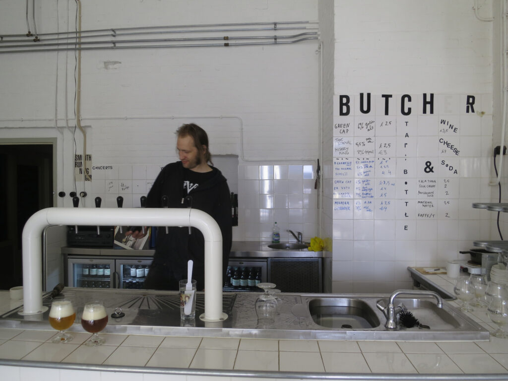 Man pouring beer behind a bar in a former abattoir