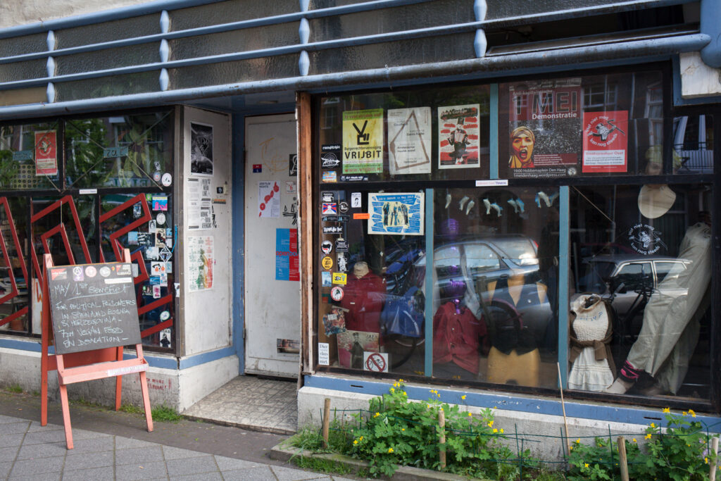 The outside of a venue with big windows and lots of posters in it.
