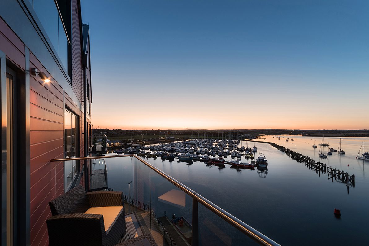 A view of a harbour at sunset from the balcony of a property.