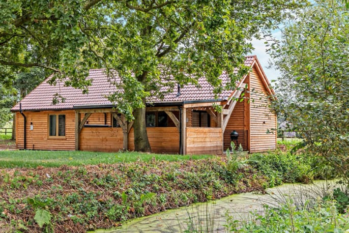 A wooden lodge set among the trees next to a stream