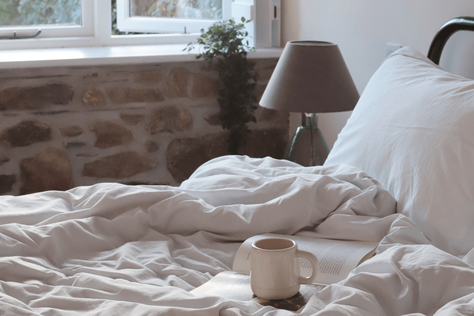 A mug lies on the unmade bed in a cosy cottage.
