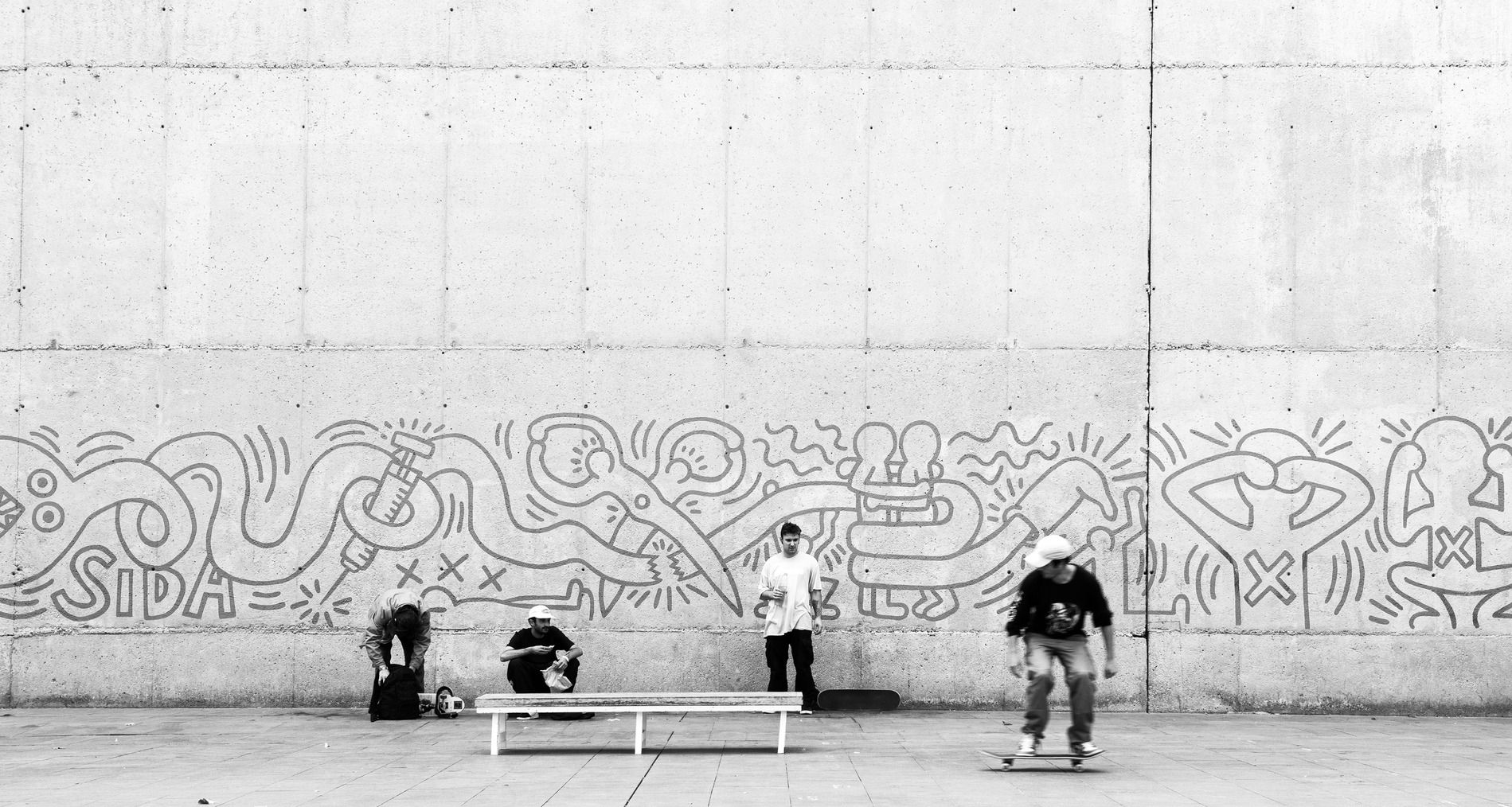 Skaters frente a un mural de arte urbano inspirado en la obra de Keith Haring, Barcelona.