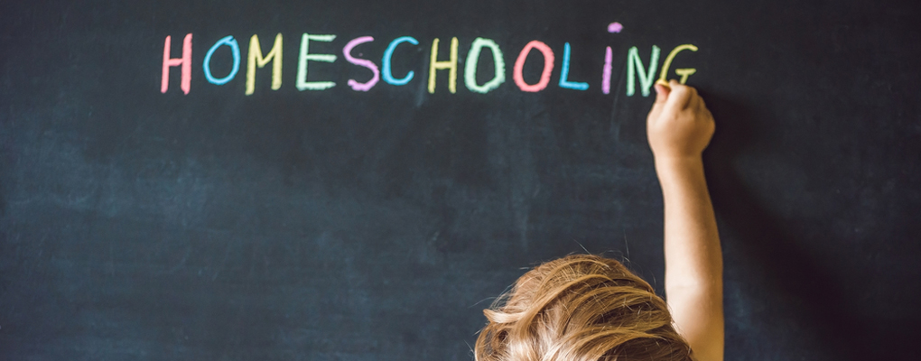 Kind schreibt Homeschooling an die Tafel