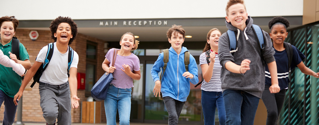 Schulkinder rennen außerhalb des Schulgebäudes