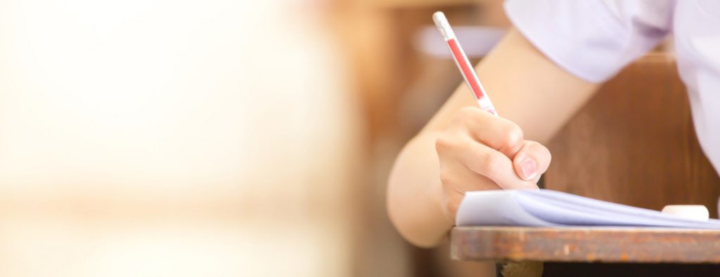 Eine Hand hält einen Stift und schreibt auf ein Blatt Papier