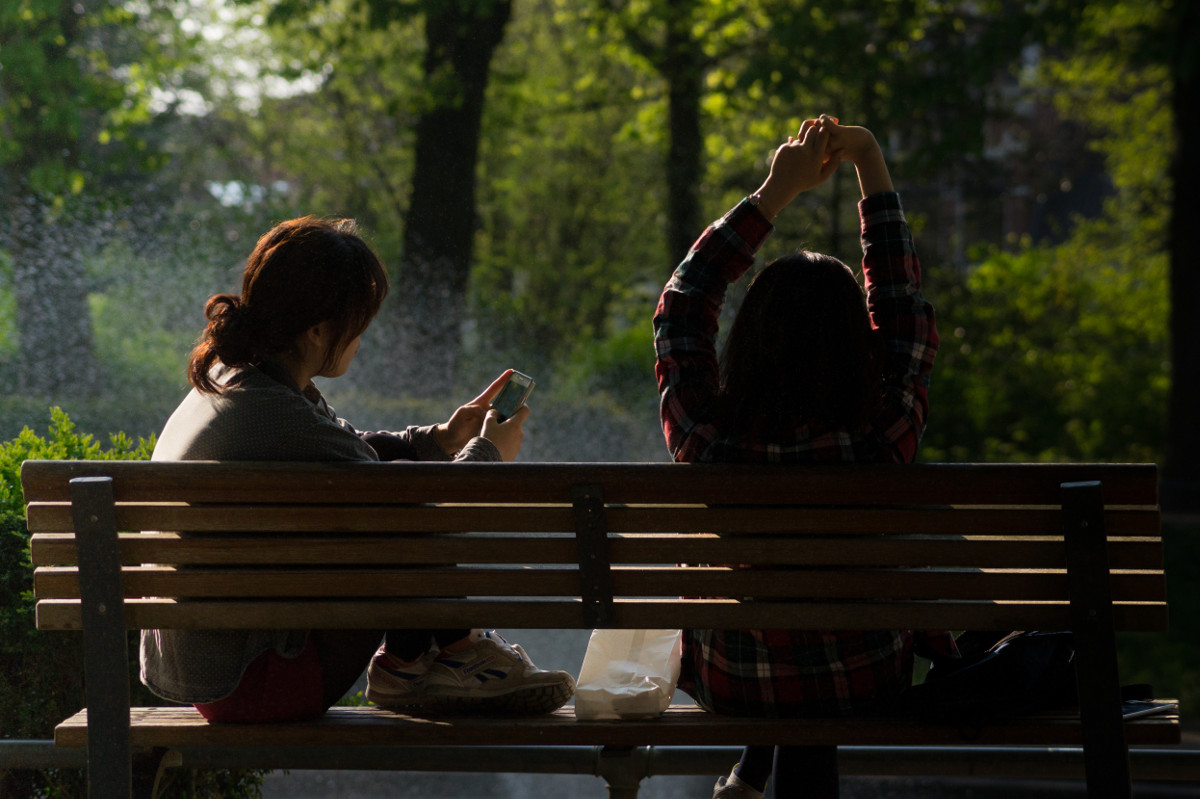 photograph picture of two women woman stretching on a park bench