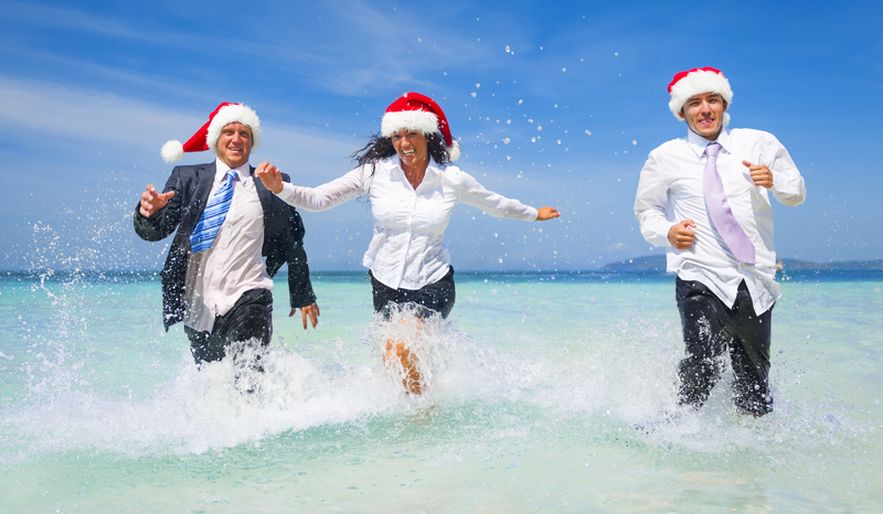 picture of office employees running through ocean wearing christmas hats