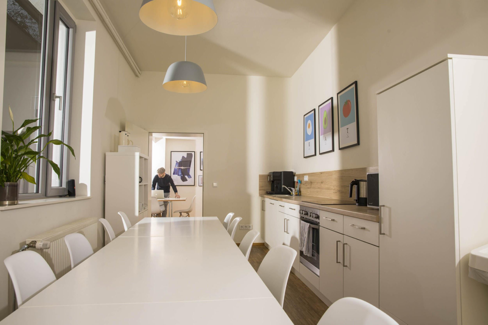 picture of a tidy office kitchen with a meeting room in the back