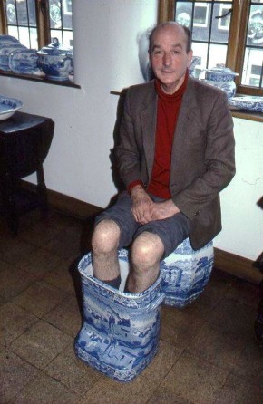 A man sitting on a ceramic seat with his feet in a large ceramic footbath