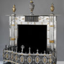 Fireplace with fender, mantel ornaments, and fire-irons, of burnished steel with applied decoration of gilt copper and brass and cut steel.
