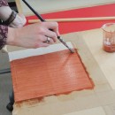 Applying the red-brown oil ground. You can already see how the paper is absorbing the oil where there is no sizing.