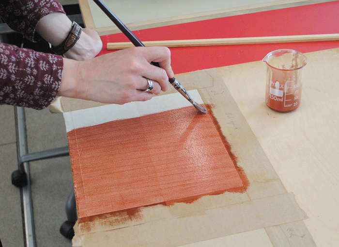 Applying the red-brown oil ground. You can already see how the paper is absorbing the oil where there is no sizing.