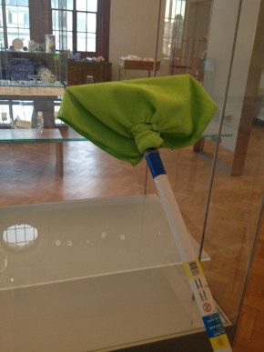 A squeegee cleaning stick with a green cloth attached