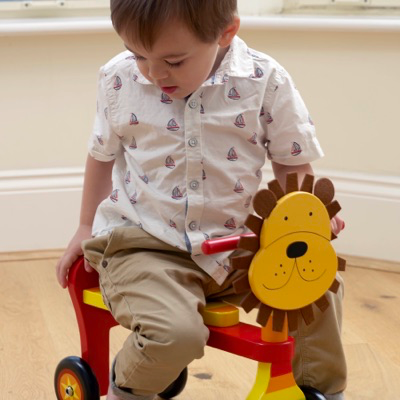 child playing on wooden Lion Trike