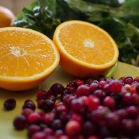 sliced orange with a pile of red cranberries in front on a plate