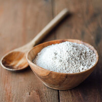 a wooden bowl of finely powdered coconut desiccated with a wooden spoon on the side