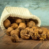 a weaved cloth basket spilling whole walnuts with shell