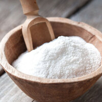 coconut finely dessicated powdered in a brown wooden bowl with a wooden spoon
