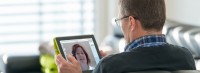 Active senior man sitting relaxed on sofa using digital tablet