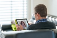 Active senior man sitting relaxed on sofa using digital tablet