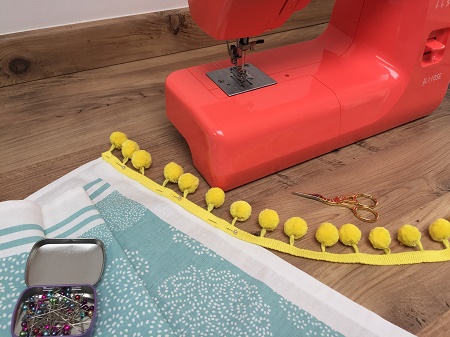 pinning pompom onto tea towel