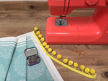 pinning pompom onto tea towel pinning pompom braid onto tea towel