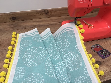 sewing pompom braid onto a tea towel sewing pompom braid onto a tea towel