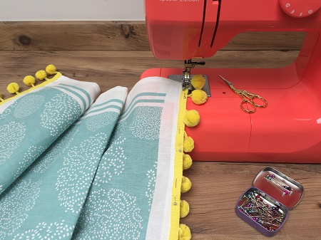 sewing pompom braid onto a tea towel