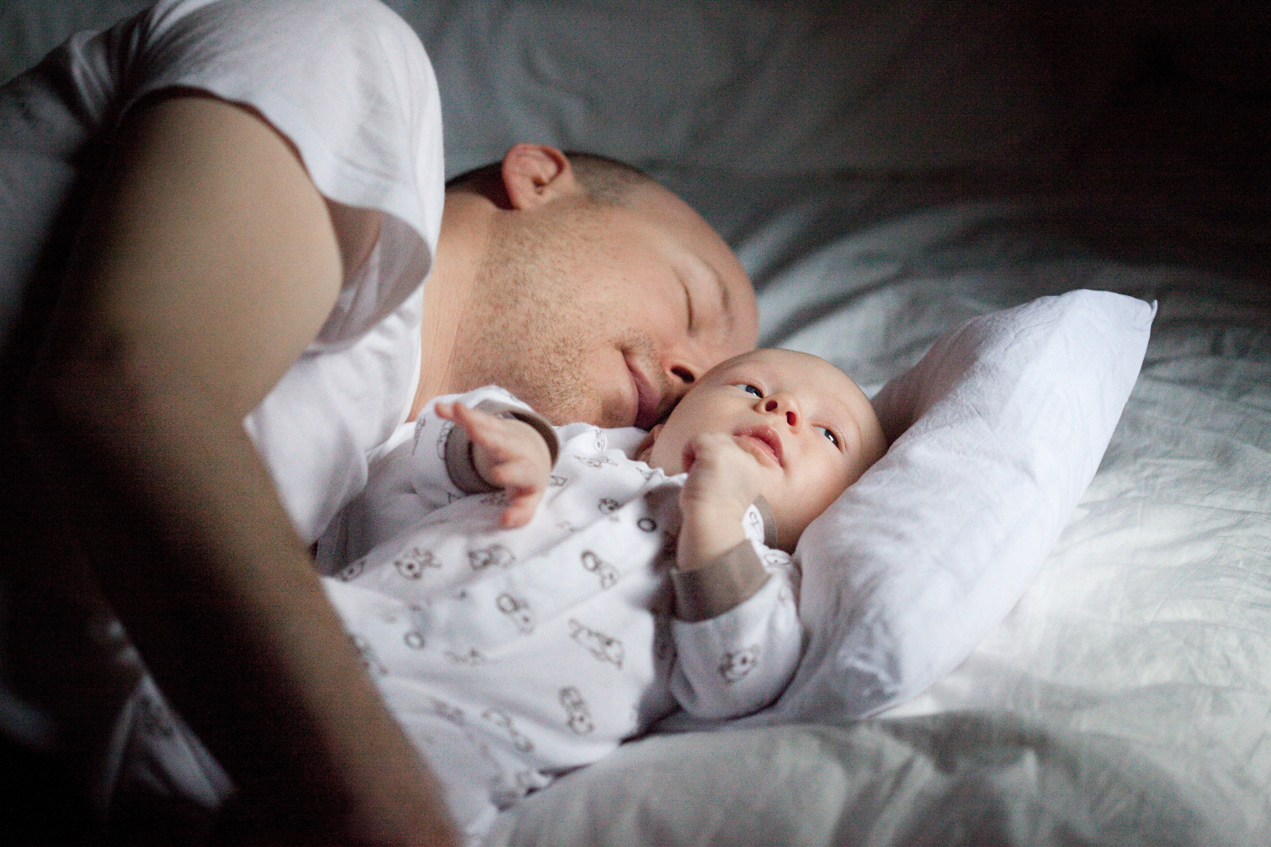 En pappa ligger och vilar med sin lilla bebis.