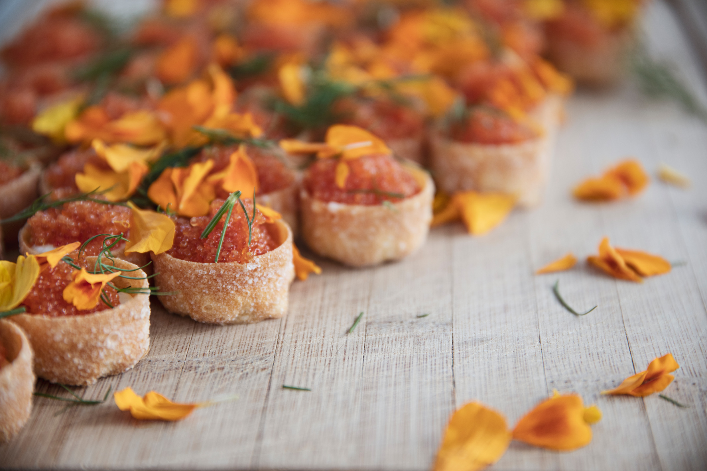 Små fyllda kanapéer på en bänk med blomblad strösslat över.